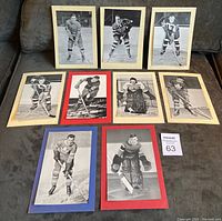 Photo showing all nine vintage hockey photos arranged on a grey couch, various players shown with original backing papers in cream, red, and blue colors.