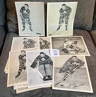 Full view of multiple 8x10 black and white photos of Toronto Maple Leafs players arranged on fabric surface, showing player poses and signatures
