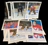 Lot of hockey photos from the 1980s spread across a surface showing various players and teams on three-hole punched pages.