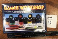 Photo of front of sealed Games Workshop Hobby Starter Set box showing paints, tools, price tag.
