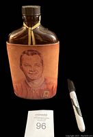Front view of the vintage Seagram's pint bottle wrapped in leather with a color portrait of Doug Harvey in Canadiens jersey.