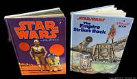 Two vintage hardcover Star Wars pop-up books side by side, showing front covers of each book with characters C-3PO and R2-D2, and Empire Strikes Back cover showing Hoth scene.