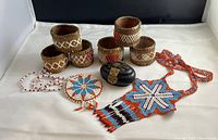Display of all items: 6 birch bark napkin rings with stitched designs, 2 beaded necklaces with colorful beadwork, small dark wood keepsake box with brass latch.