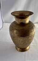 Full view of brass vase showing overall shape and engraved designs on body and neck.