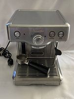 Front view of stainless steel Breville espresso machine showing controls and portafilter on drip tray