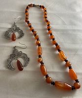 Overall set showing amber-colored stone necklace and matching earrings with intricate silver designs.