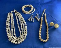 Full view of the jewelry set on blue cloth including necklaces, bracelets, and earrings.