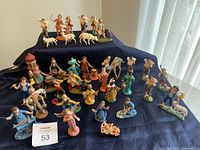 Full overview of the large set of nativity figurines displayed on a blue cloth, showing all characters and animals.