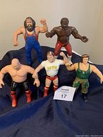 Photo showing all five WWF rubber wrestling figures arranged standing on a dark fabric background to display full front views and size.