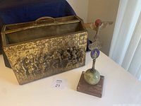 Both the brass magazine caddy and the Legio Mariae statue displayed side-by-side on a white surface, showing the height and design of both items.