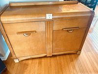 Front view of wooden sideboard with curved waterfall front edges and two drawers above double doors