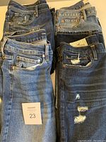 Top-down view showcasing six pairs of blue denim jeans stacked, showing variety in color and wear.