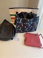 Four handbags arranged on a table showing varying styles and colors.