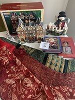 Overall lot showing Lemax Ski Lodge, Christmas stockings, snowman figure, books, and holiday fabrics.