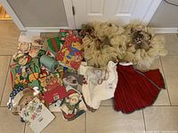 Photo showing two handmade beige mesh wreaths with burgundy floral accents along with assorted colorful gift bags and boxes featuring holiday and character designs.