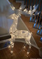 Full view of the illuminated reindeer decoration showing its size, shape and lighting arrangement indoors on hardwood floor near staircase.