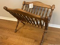 Wooden Tell City maple magazine rack with spindle design shown from side angle on hardwood floor.