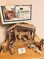 Photo showing original Sears box and ceramic nativity set stable with figurines arranged in front.
