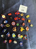 Overview of many colorful superhero-themed shoe charms including Spider-Man, Batman, Captain America, Pikachu, and more.
