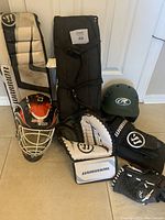 View showing all included items in the hockey set with goalie pads, catcher glove, blocker, helmets, and gloves