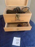 Open wooden box showing the electric shoe polisher and magnetic attachments inside the lower drawer