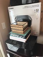 Canon Pixma MX922 printer with original box behind and basket with papers stacked on top.