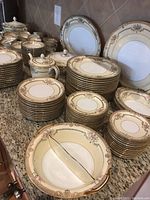 Stacks of plates in four sizes with cups and saucers, terrines visible at left