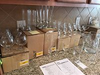 Complete view of crystal barware placed on counter showing multiple glasses and boxes with labels