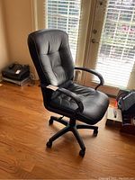 Front-angle view of black vinyl desk chair showing padded seat and backrest, armrests, and caster wheels.