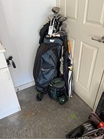 Full view of the Nike golf bag standing next to a door in a garage, showing the bag with clubs inside and an umbrella attached.