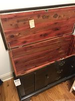Opened cedar chest showing natural cedar lining inside and hinged top lid with Lane brand marks and attached key tag.