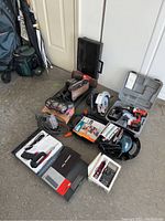 Overview of all power tools and cases arranged on the floor showing variety of tools included in the lot.