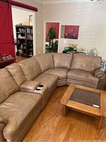 Front view of complete beige sectional sofa on hardwood floor with coffee table.