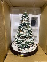 Boxed Thomas Kinkade Village Christmas tree inside protective foam packaging with power cord.