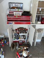 Silver Craftsman toolbox on top of red Snap-on toolbox drawers, open cabinet below showing tools