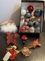 Top view of box showing assortment of glass baubles and various other holiday decorative ornaments including wood angel, reindeer with faux fur, butterflies, and small pieces.