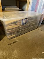 Clear plastic tote containing a large quantity of stacked magazines and pattern bundles.