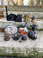 Overview of all decorative items displaying variety including metal candle holders, cast iron figurines, ceramic pieces, and resin decor.