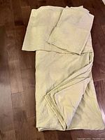 Full view of folded light celery duvet cover and matching pillow shams on floor