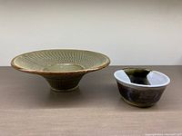 Two studio pottery bowls side by side on a table, showing size difference and glazes.