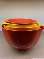Side view of four nested vintage Danish Rosti MEPAL melamine mixing bowls in red and yellow.
