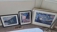 Three framed posters on a floor against a wall: Monet, Hopper, and Van Gogh artworks