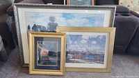 Framed artworks arranged together showing three frames with various outdoor scenes