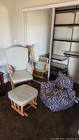 Glider chair with matching ottoman and zebra print children's bean bag chair in a room with carpet and closet behind them.