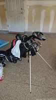 Wide view of golf bag with 19 clubs standing on garage floor.