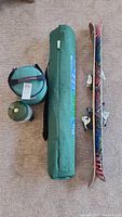 Photo showing skis with bindings, green camping cot in cylindrical bag, and Coleman lantern with carrying bag.