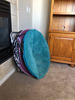 Three folded papasan chairs stacked together, showing cushion colors and foldable metal frames.