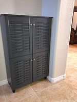 Full front view of the gray storage cabinet with all four woven doors closed, showing the overall design, color, and shape.