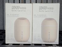 Photo of the front of two boxed bottle humidifiers, tan color visible on packaging, labeled 'Bottle humidifier'