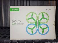Front view of boxed Eachine E65HW LED quadcopter drone with green and blue propellers and LED accents.